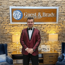 a man in a red tuxedo and bow tie is standing in front of a stone wall .