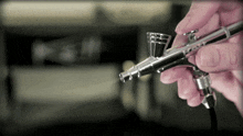 a person holding an airbrush in their hand