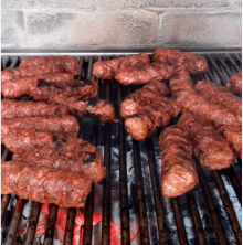 a bunch of sausages are cooking on a grill with red flames