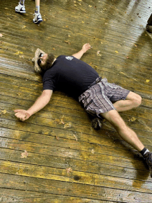 a man laying on a wooden deck wearing sunglasses and a hat