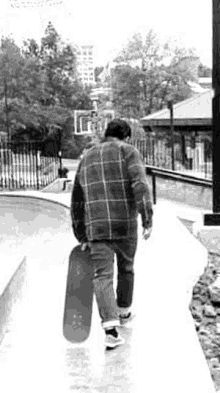 a man is walking down a sidewalk with a skateboard .