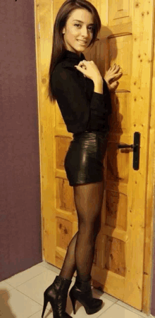 a woman standing in front of a wooden door wearing tights and high heels