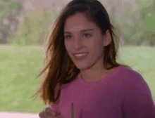 a woman in a pink sweater is smiling while holding a pencil