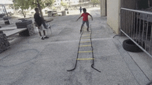 a boy in a red shirt is jumping over a ladder .