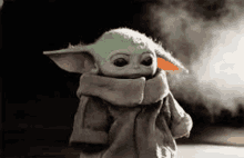 the baby yoda from star wars is wearing a scarf around his neck and standing in front of a cloud of smoke .