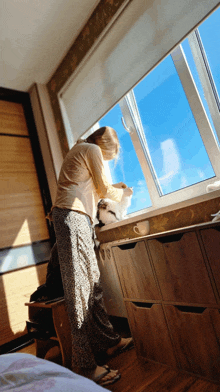 a woman standing in front of a window with a blue sky in the background