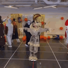 a woman in a scarecrow costume is standing on a tiled floor in front of a group of people in halloween costumes .