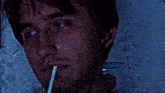 a man is smoking a cigarette with a straw in his mouth in a dark room .