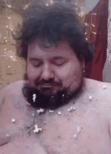 a shirtless man with a beard is covered in popcorn on his chest .