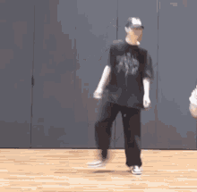 a man is dancing on a wooden floor in a room while another man watches .