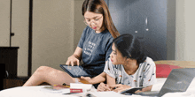 a girl wearing a t-shirt that says train for a courageous warrior looks at a tablet