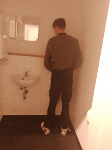 a man standing in a bathroom next to a sink and a mirror