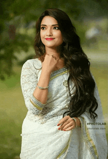 a woman wearing a white lace blouse with a gold border is standing in a field