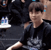 a young man is sitting in a chair in front of a table with bottles of water on it .