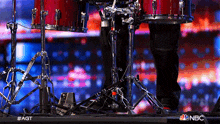 a person is playing drums on a stage with a nbc logo in the corner