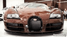 a brown bugatti veyron is parked in a showroom next to other cars .