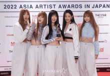 a group of girls pose for a photo in front of a sign that says asia artist awards in japan