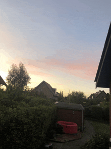 a sunset over a backyard with a red hot tub and a shed