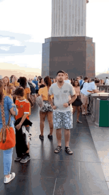 a group of people standing in front of a statue with a man wearing shorts that say ' hawaii ' on them