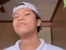 a young man wearing a white baseball cap and a white shirt