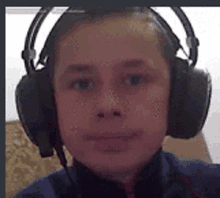 a young boy wearing headphones is taking a picture of himself .