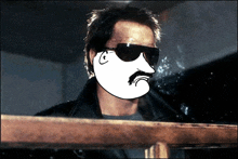 a man wearing sunglasses and a mustache is smoking a cigarette in a dark room