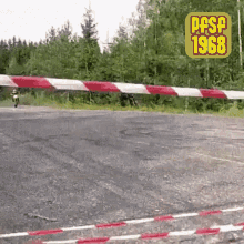 a person on a motorcycle going over a red and white striped barrier with the year 1968 on the top