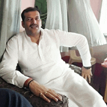 a man wearing a white shirt is sitting on a couch