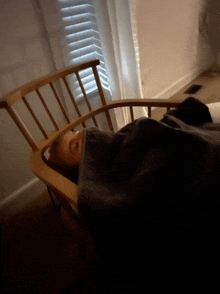 a person laying in a chair with a black blanket