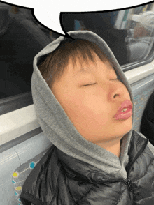 a young boy wearing a hoodie is sleeping on a train