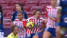 a woman in a red and white striped jersey with the number 18 on it is holding a soccer ball