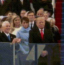 a man in a suit and tie is shaking hands with a woman in a blue coat in front of a crowd of people .