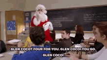 a man dressed as santa claus is standing in a classroom with a group of students sitting at desks .