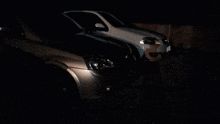 a white car is parked next to a black car in the dark