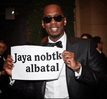 a man in a tuxedo holds a sign that says jaya nobtk albatal