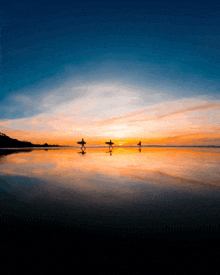 three surfers carrying their surfboards on the beach at sunset