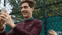 a man in a purple sweater is taking a picture of himself with the words " what the cut " written below him