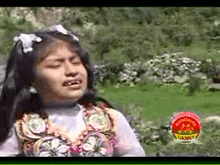 a little girl is standing in a field with her eyes closed