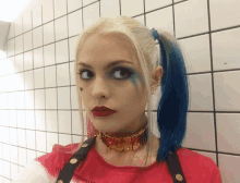 a woman in a harley quinn costume is standing in front of a white tiled wall