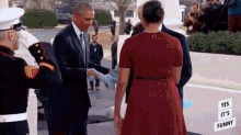 a man in a suit and tie is shaking hands with a woman in a red dress in front of a white house .