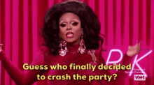 a drag queen is standing in front of a pink curtain .