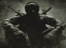 a soldier in a gas mask is kneeling down with two guns behind his back .