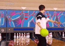 a boy is playing bowling with a yellow ball in front of a wall that has the number 9 on it