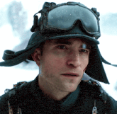 a man wearing a hat and goggles looks at the camera with a serious look on his face