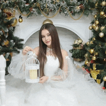 a woman in a white dress is holding a bird cage with a candle inside