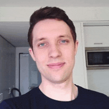 a man is taking a selfie in a kitchen and smiling .