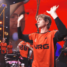 a man wearing a nrg jersey holds up his hands in the air