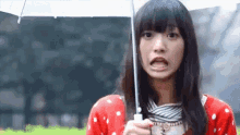 a woman in a red and white polka dot shirt is holding an umbrella .