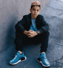 a boy sits on the ground wearing a pair of blue shoes that say human