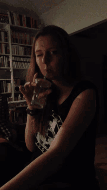 a woman drinking through a straw wearing a black shirt that says ' auckland '